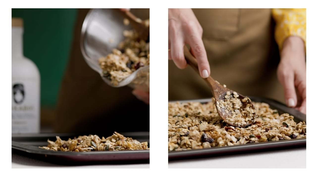 Granola being spread out evenly on a baking sheet before being placed in the oven.