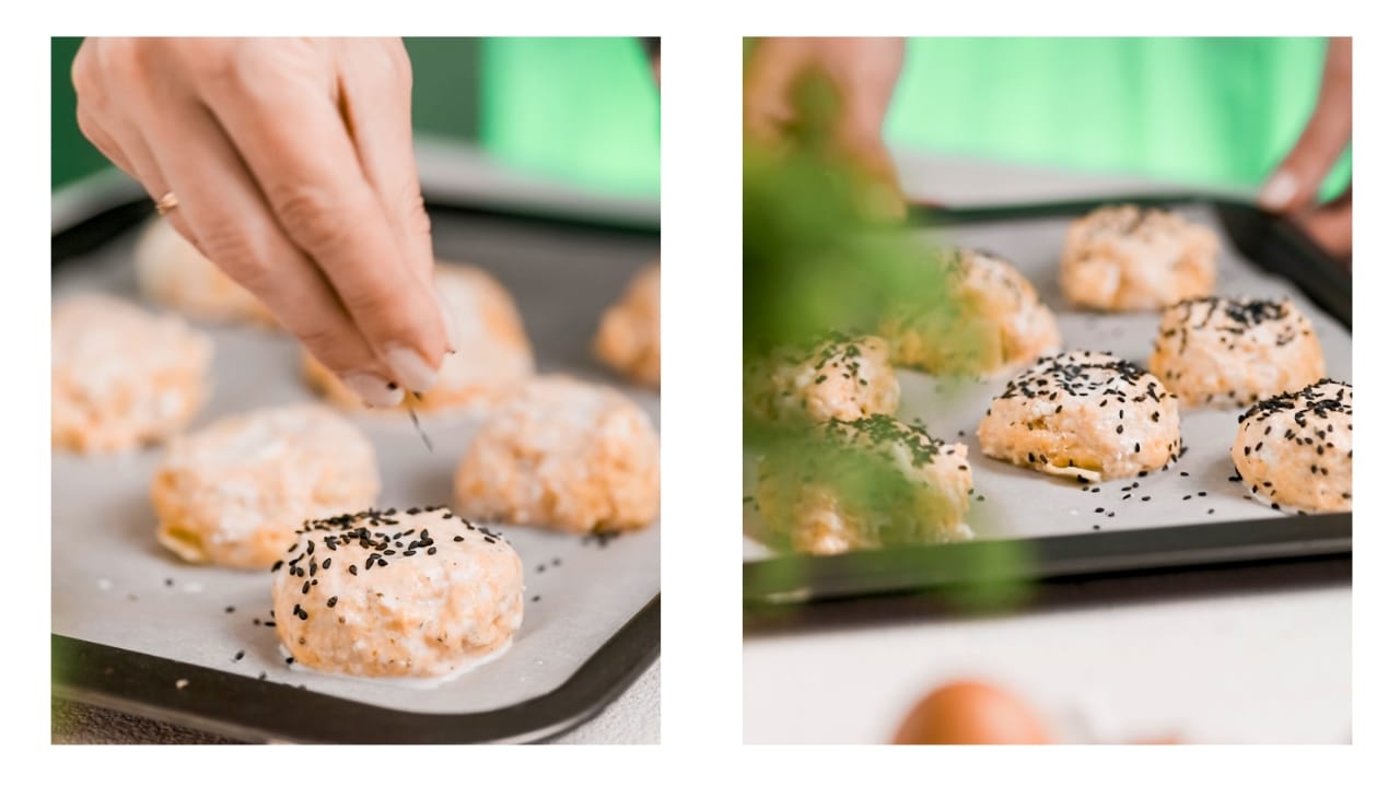 Poppy seeds being sprinkled over buns that are ready to go in the oven.