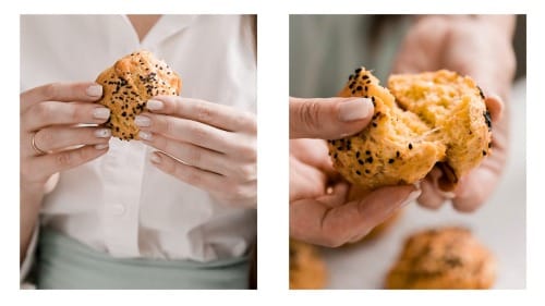 A chef holding a tiropita koulouriou and opening it to show all how delicious this bread and cheese bun is.