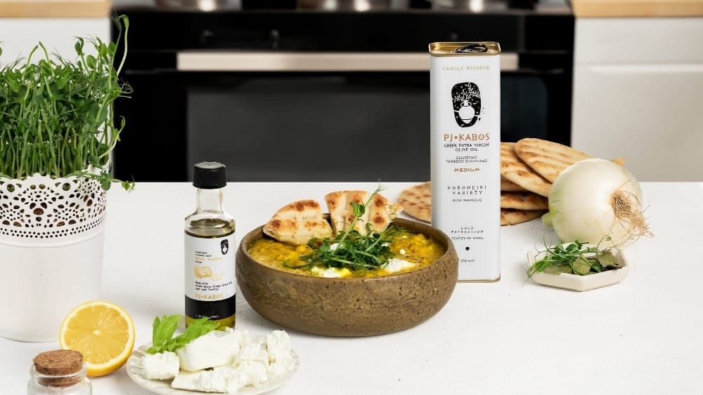 A scrumptious and healthy bowl of Greek/Mediterranean Yellow Split Pea Soup made with PJ Kabos High-Phenolic Extra Virgin Olive Oil, surrounded by some of the fresh ingredients used in its preparation.