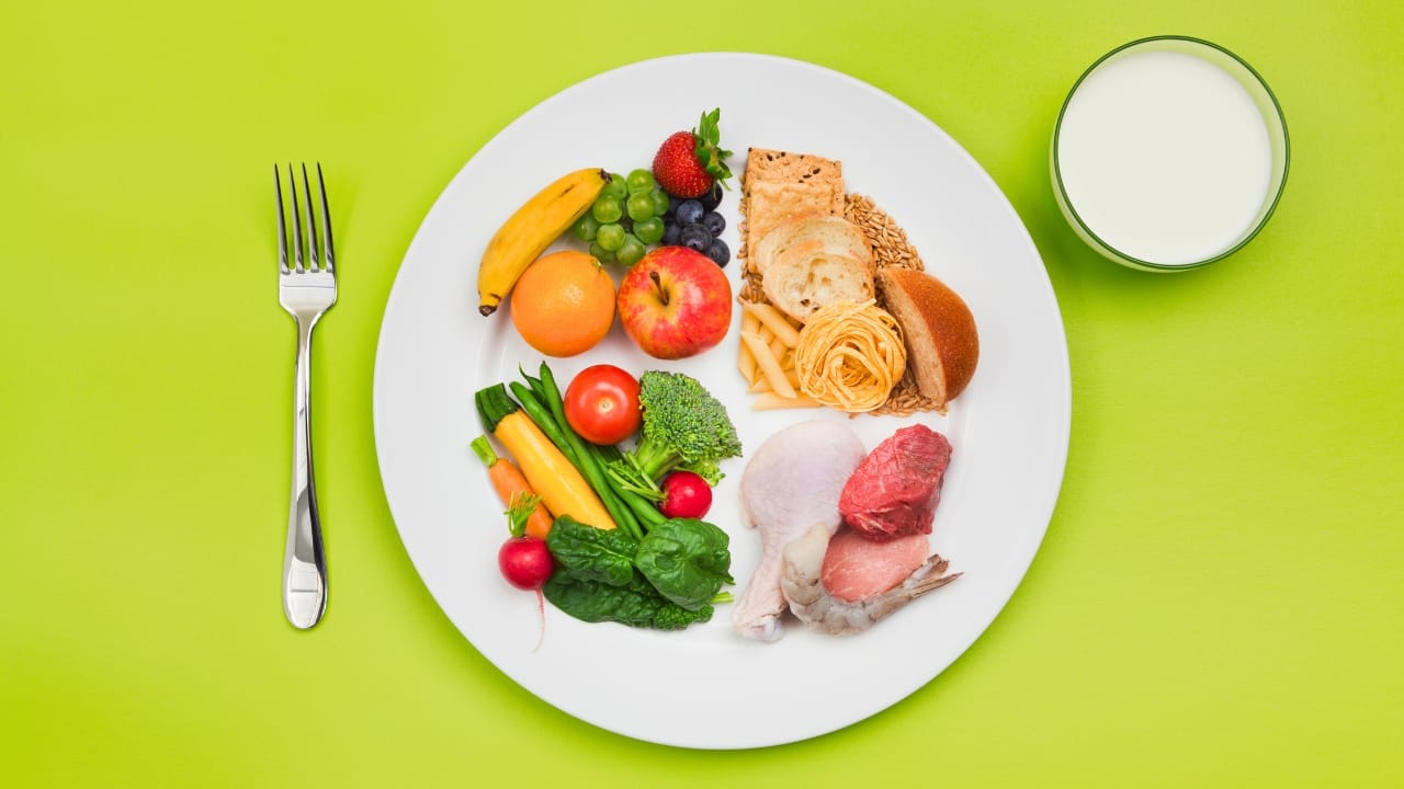 A plate showing a balanced diet; half the plate has vegetables and fruit and the other has whole grains and protein.