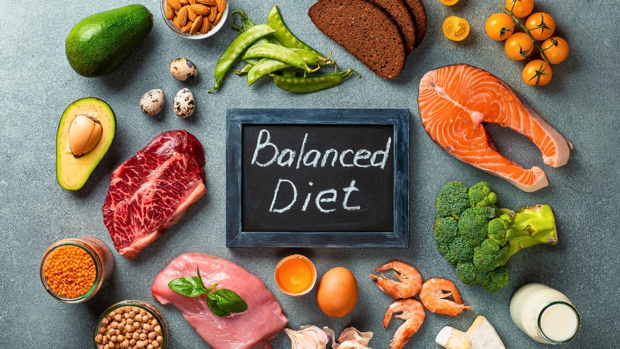 The ingredients of a balanced diet around a chalkboard writing "Balanced Diet."