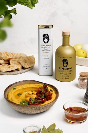 Fava, pita bread, a bottle and a tin of Extra Virgin Olive Oil, all set on a table waiting to be eaten.